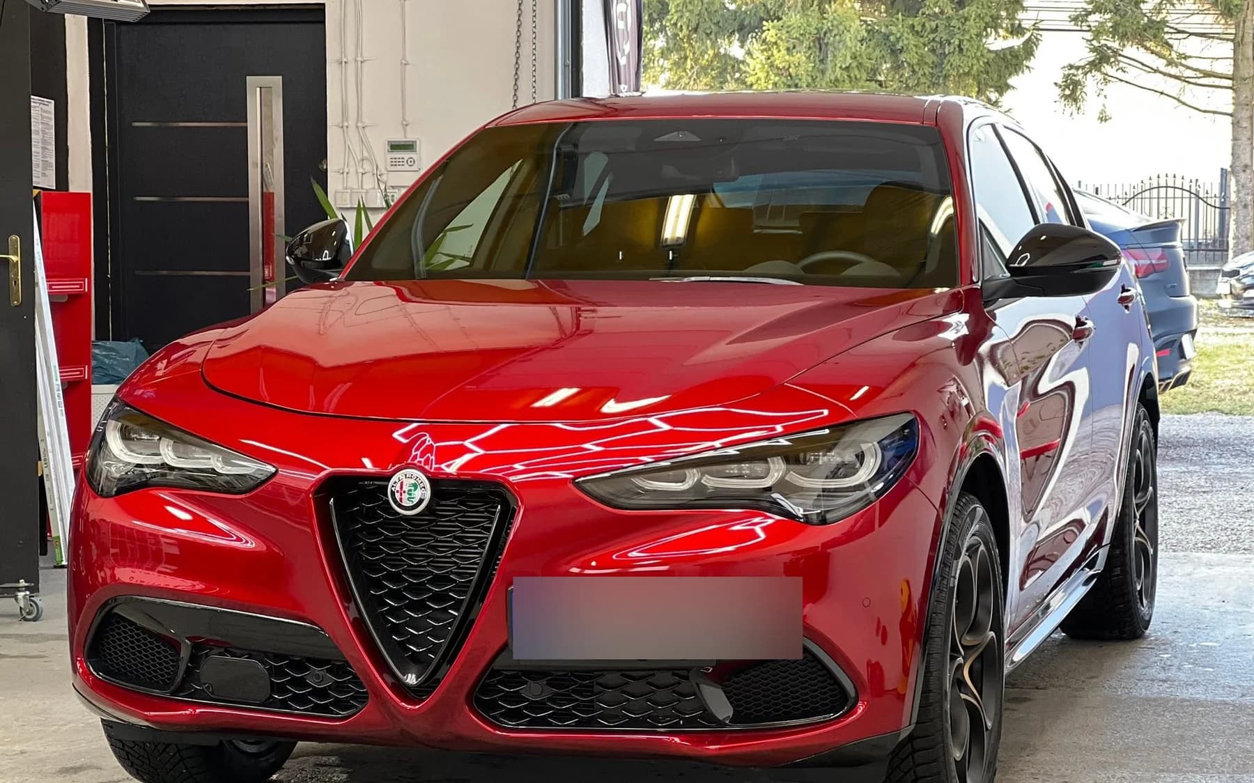Czerwona Alfa Romeo Stelvio po korekcie lakieru — ostre odbicia i głęboka czerwień na masce i błotnikach.