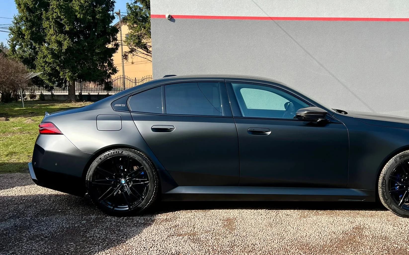 BMW M5 w satynowej ciemnej szarości, pełny profil auta sfotografowany przed studiem Auto Estetyka w Krakowie.