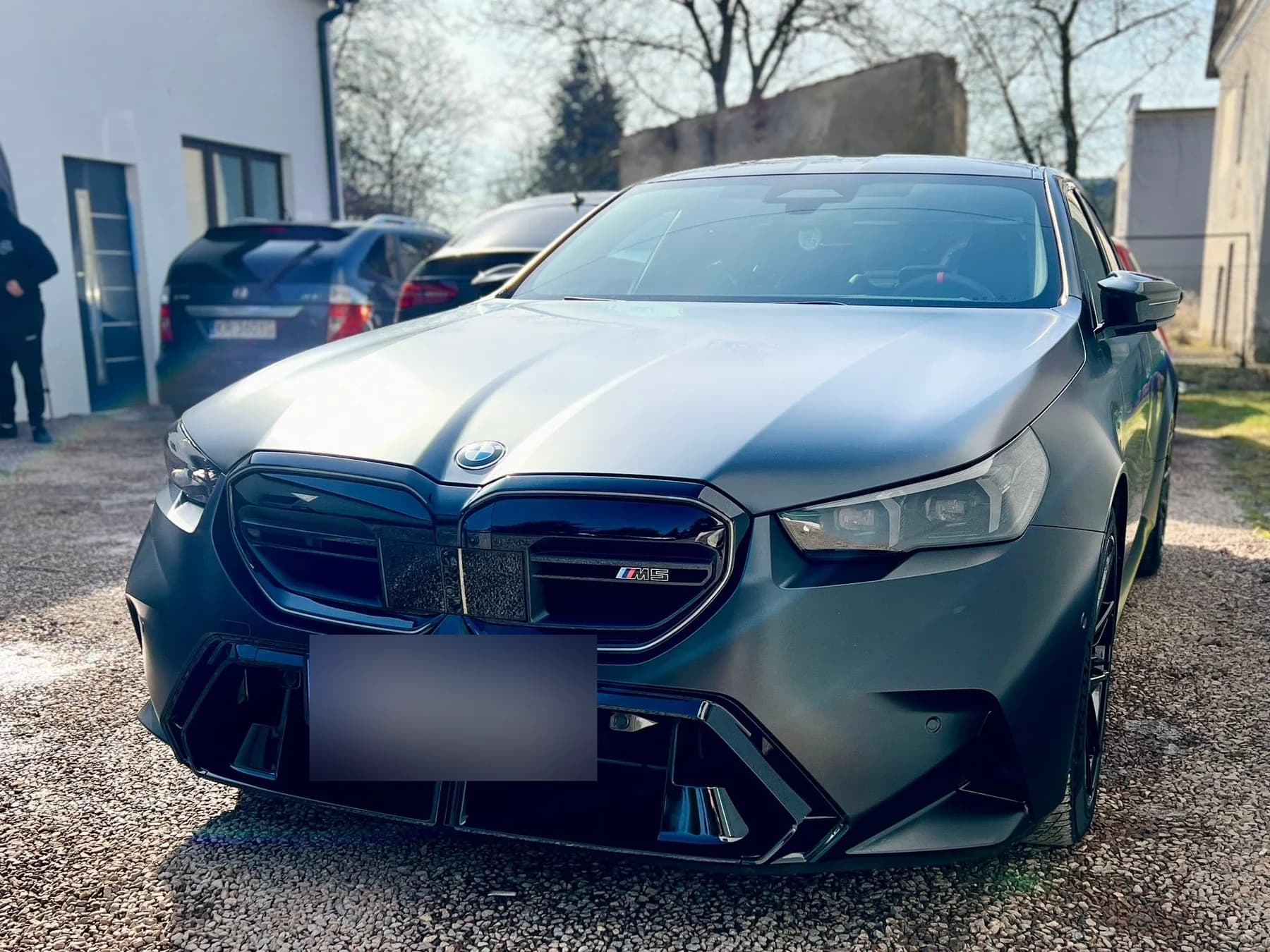 Przód BMW M5 po zmianie koloru na satynową szarość — widoczna atrapa i reflektory po aplikacji folii.