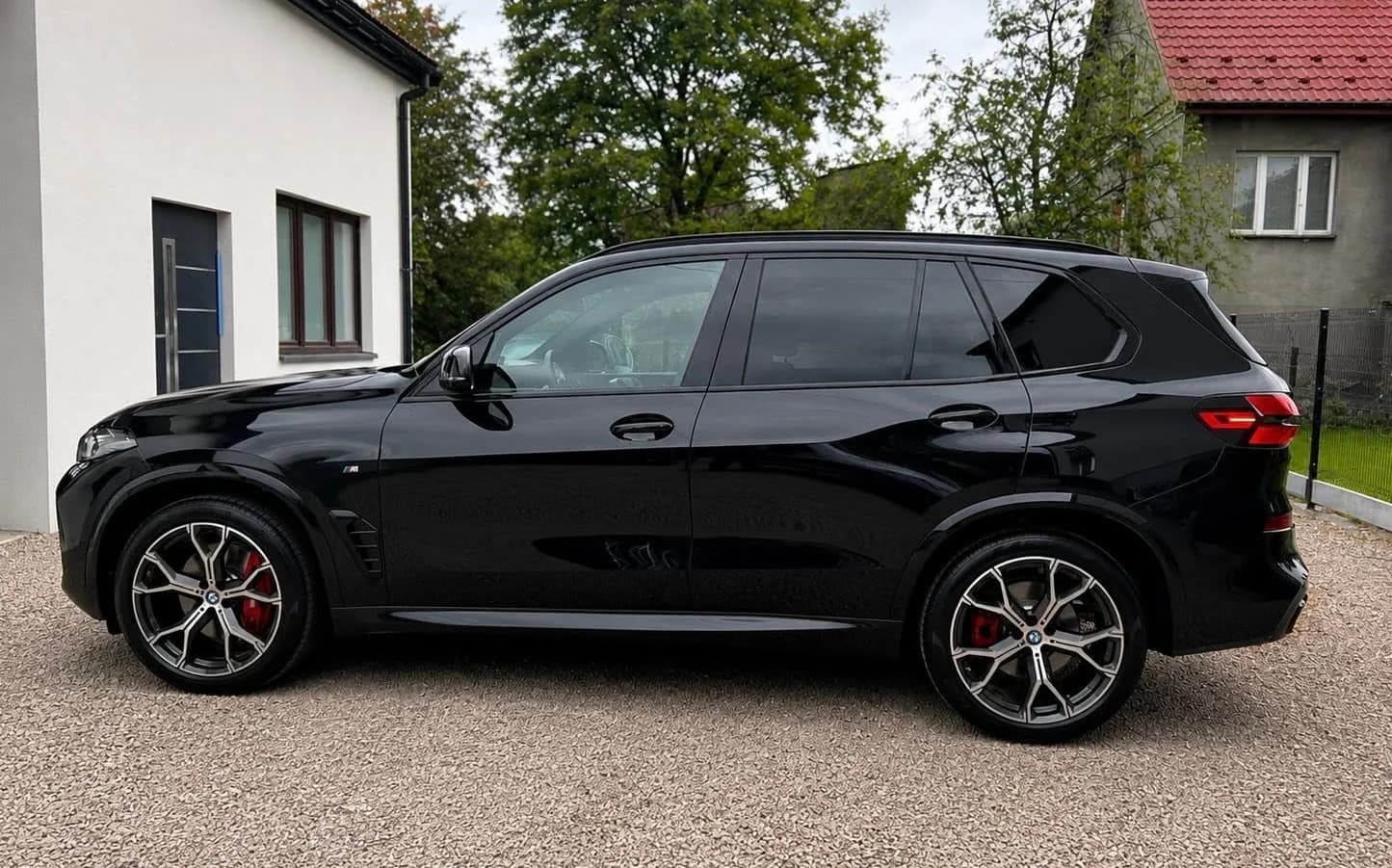 Czarne BMW X5 z profilu przed budynkiem studia — lakier po detailingu i zabezpieczeniu.