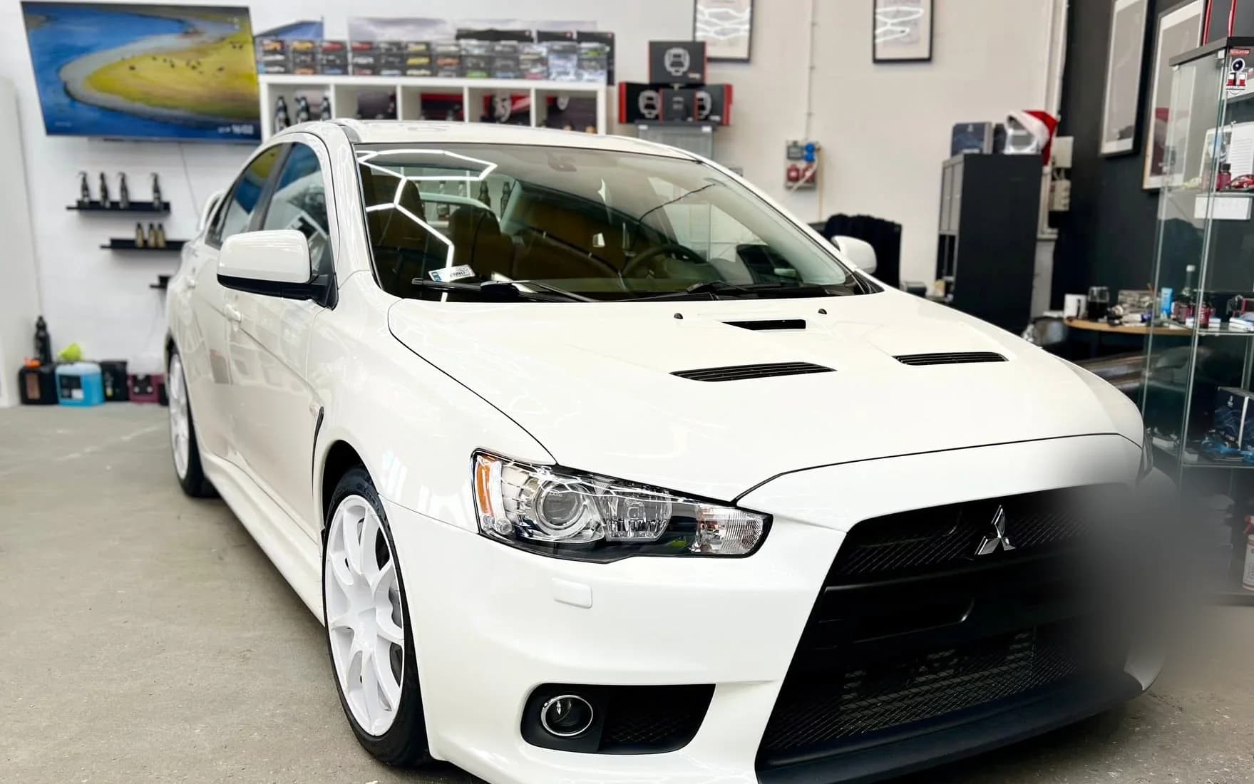 Białe Mitsubishi Lancer Evolution X po zakończonym detailingu, ustawione w hali studia.