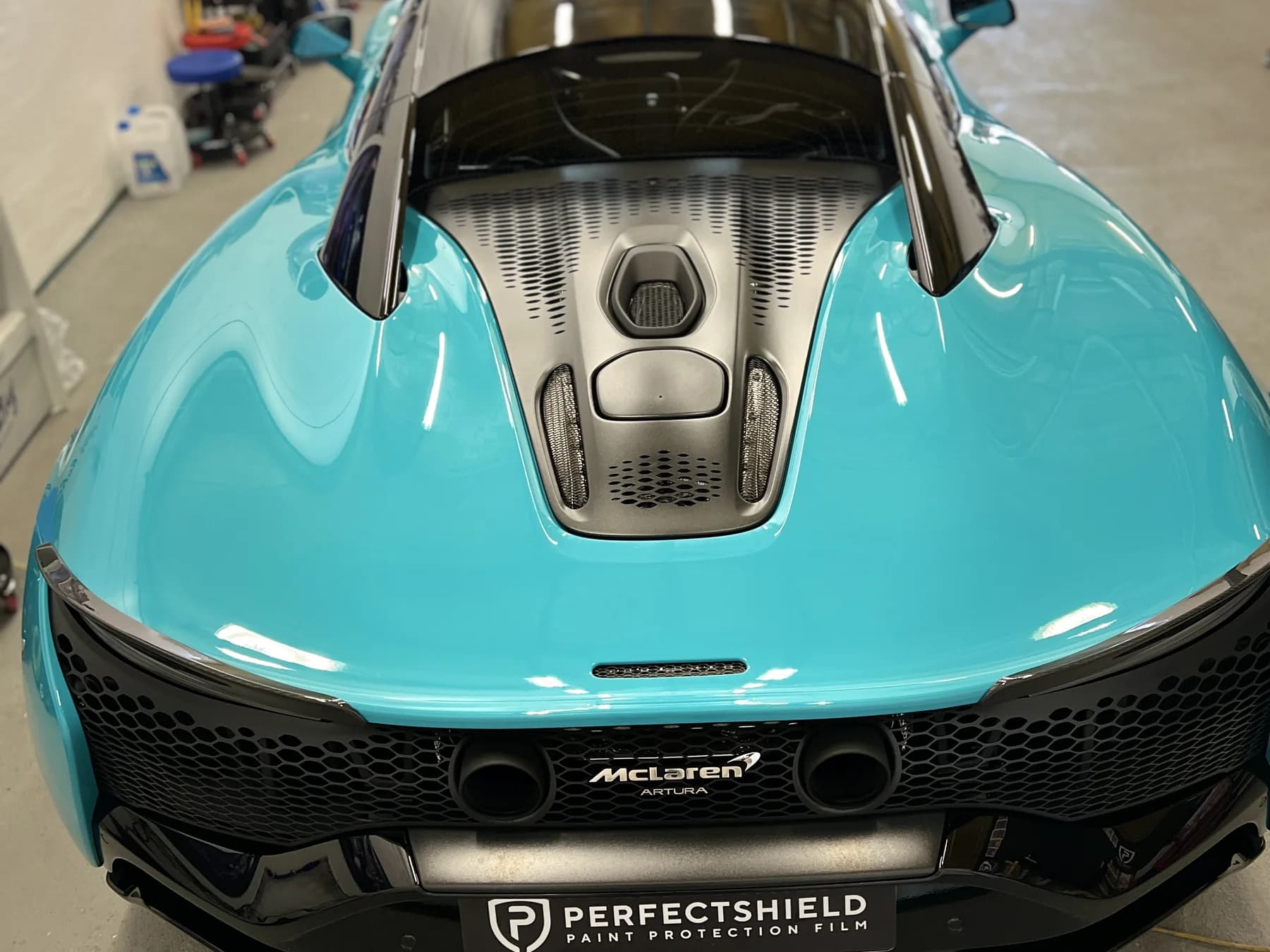 McLaren Artura w miętowym lakierze w hali studia Auto Estetyka — przód auta zabezpieczony folią ochronną PPF.