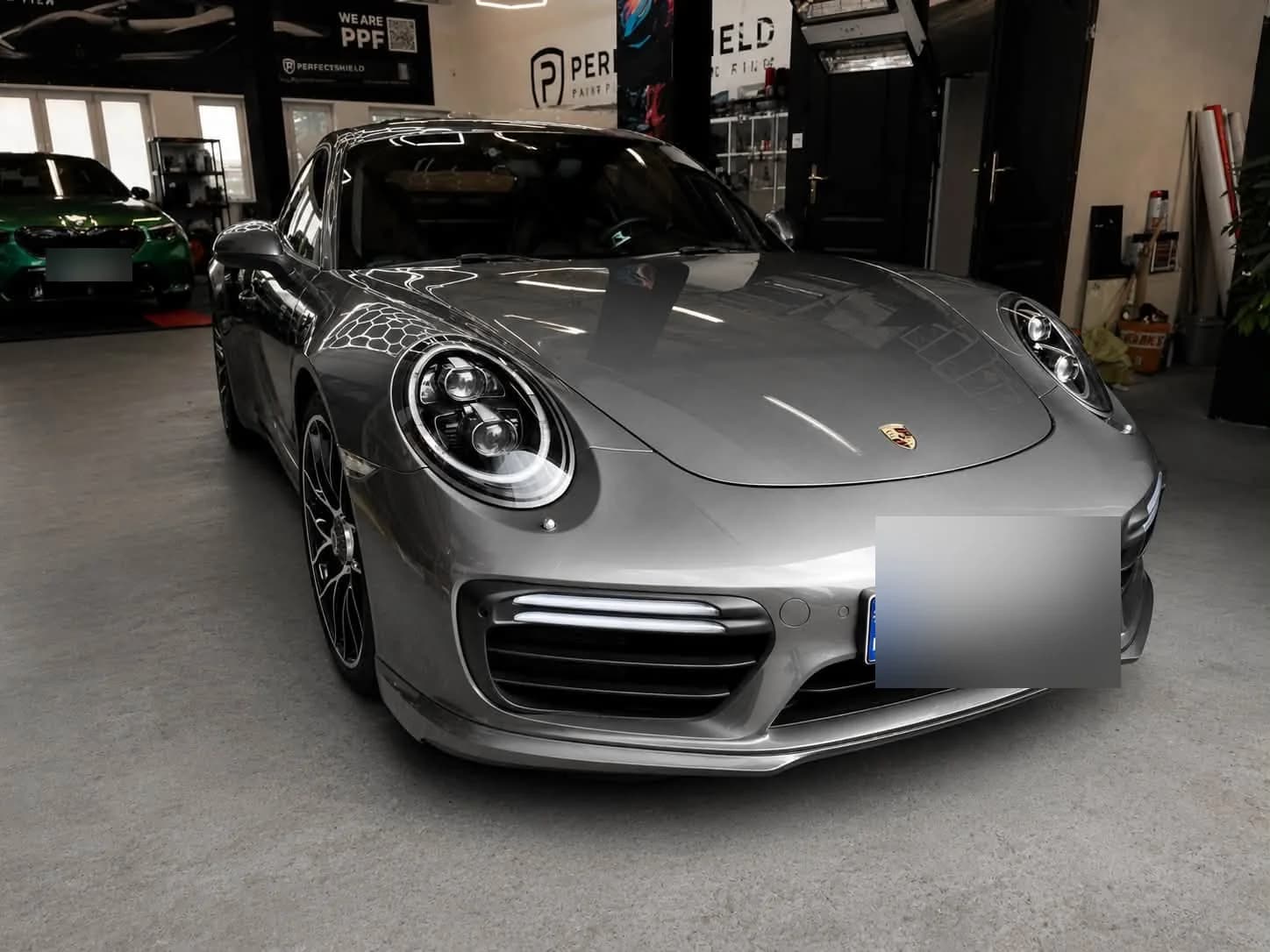 Srebrne Porsche 911 Turbo S w hali studia, ujęcie z przodu pod skosem — lakier po pełnej pielęgnacji.
