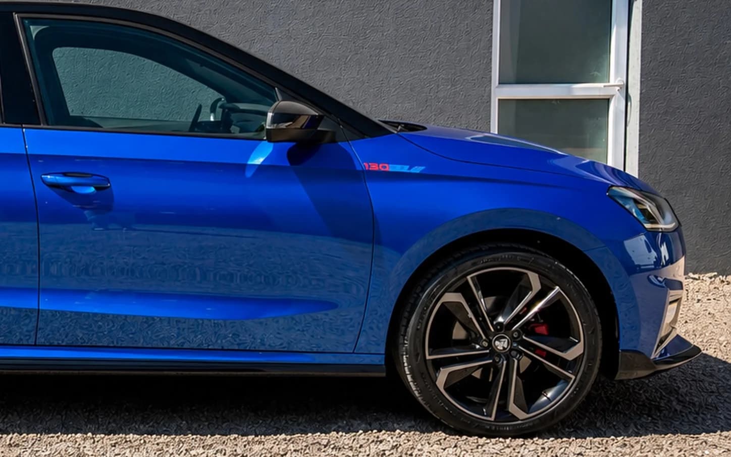 Niebieska Škoda Fabia Monte Carlo z profilu przy ścianie studia — lakier po powłoce ceramicznej lustrzanie odbija otoczenie.