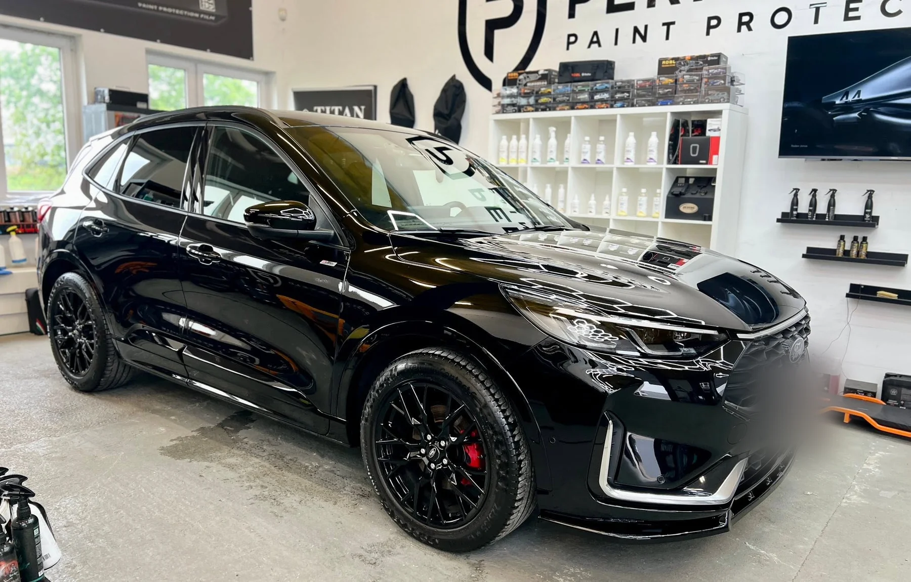 Czarny Ford Focus ST-Line w hali studia po detailingu nadwozia — lakier odbija oświetlenie sufitowe.