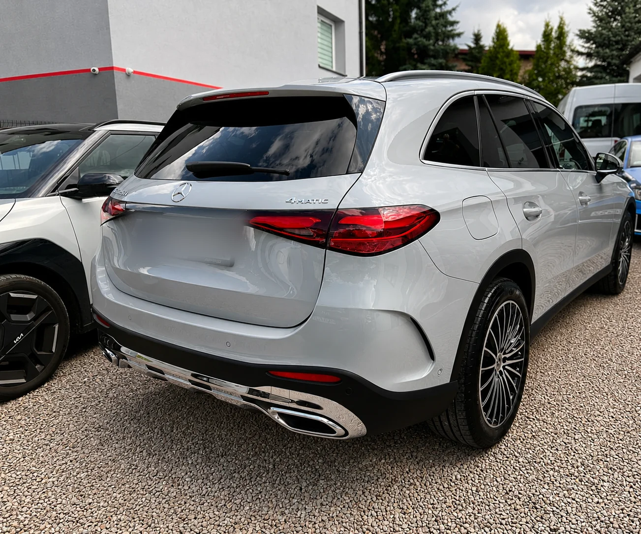 Srebrny Mercedes GLC nowej generacji pod skosem od tyłu po pielęgnacji lakieru, przed halą studia.