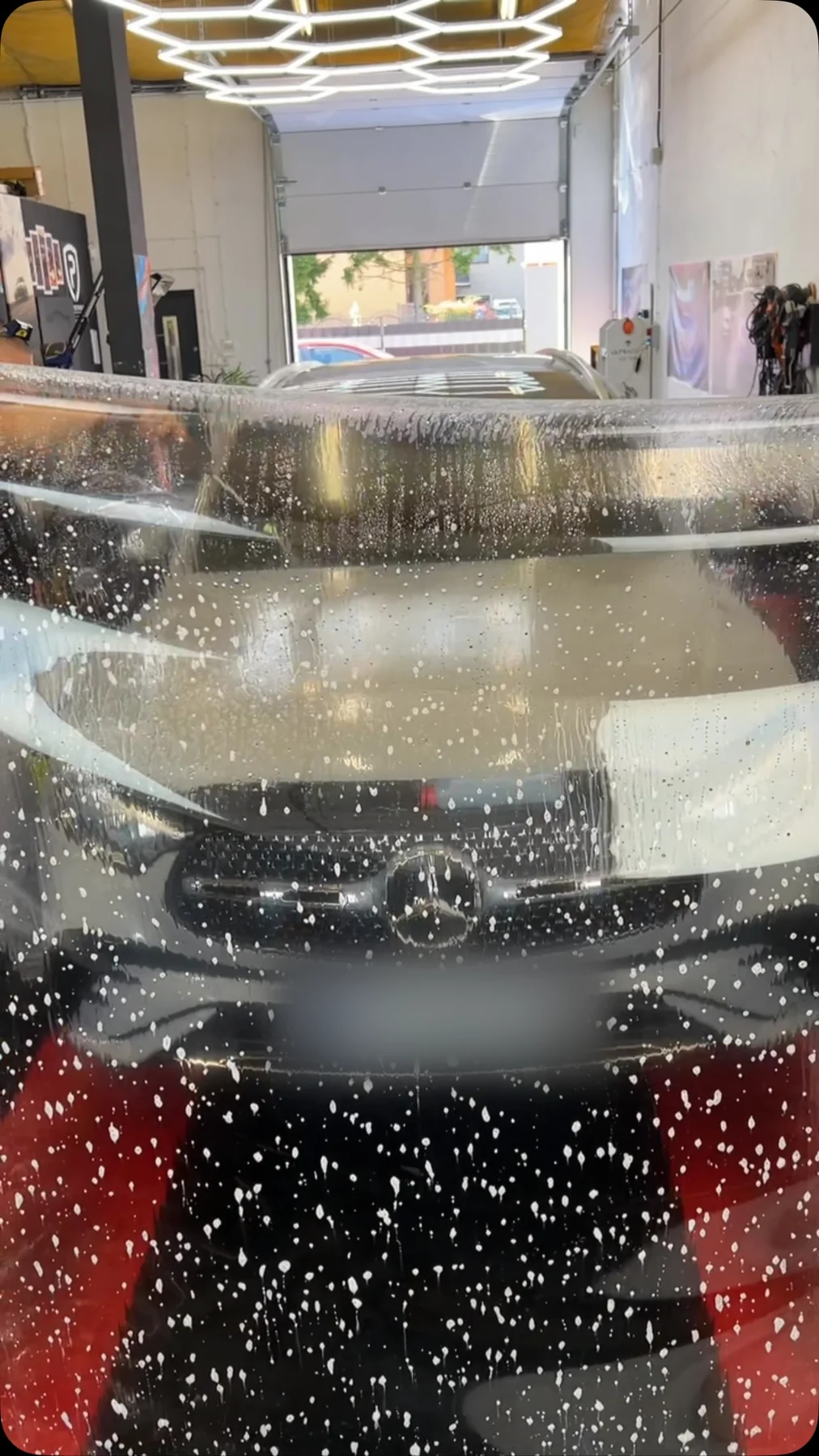 Woda perli się na masce białego Mercedesa po nałożeniu powłoki ceramicznej — kropla nie rozlewa się w plamę.