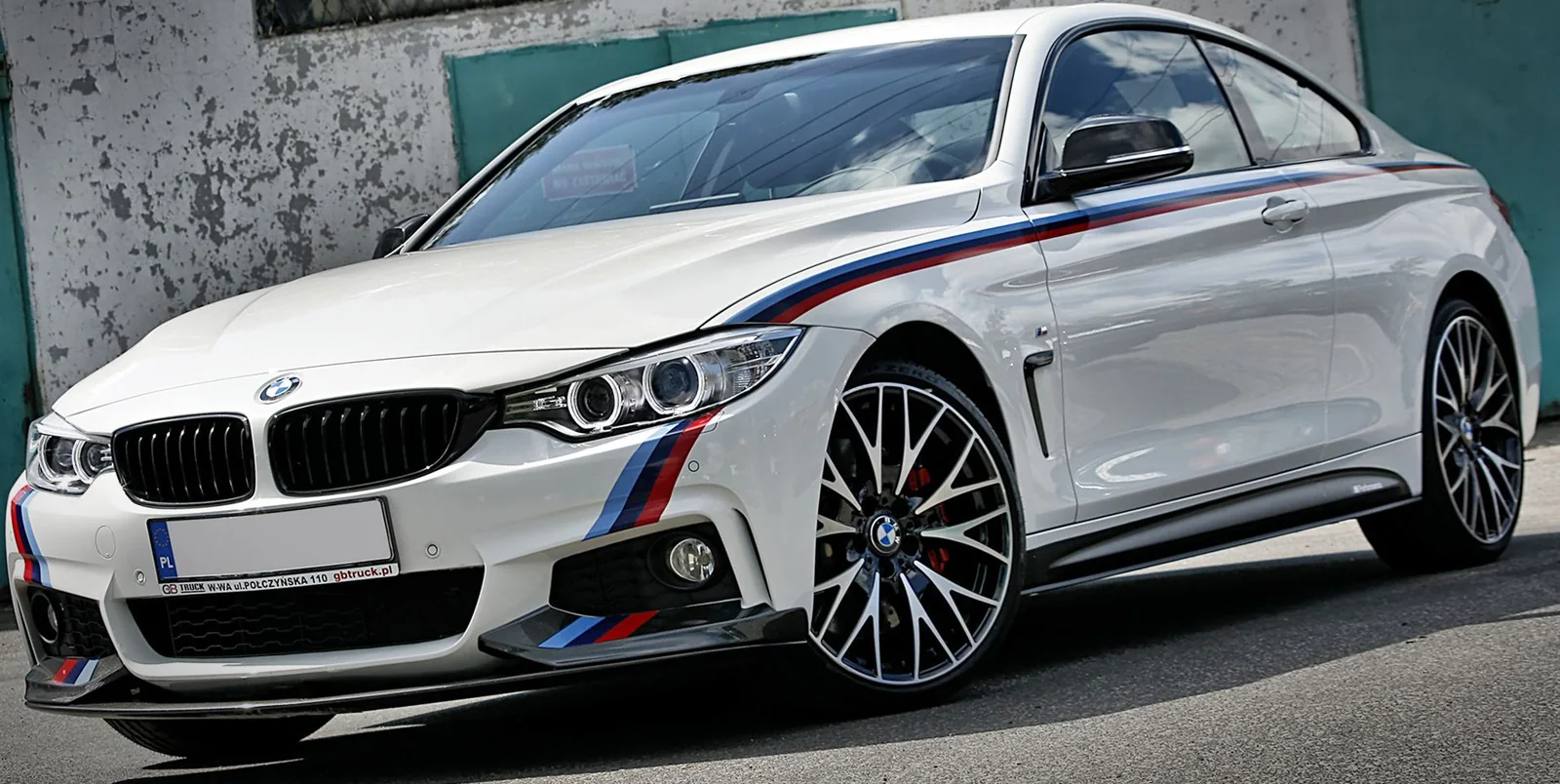 Białe BMW serii 4 z pasami M naklejonymi na drzwiach i błotniku
