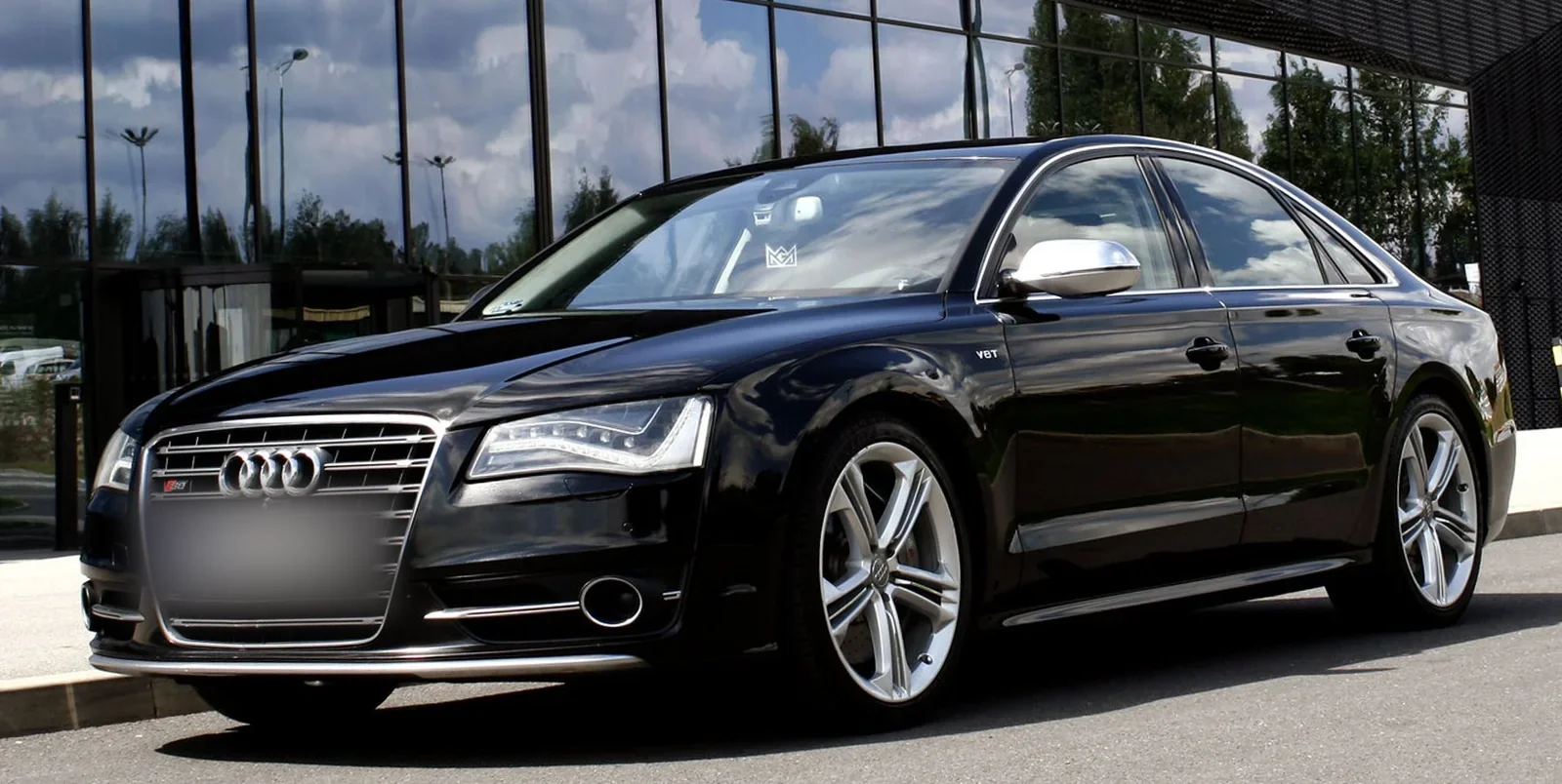 Czarne Audi S8 po pełnym detailingu — lakier z lustrzanym odbiciem szklanej elewacji