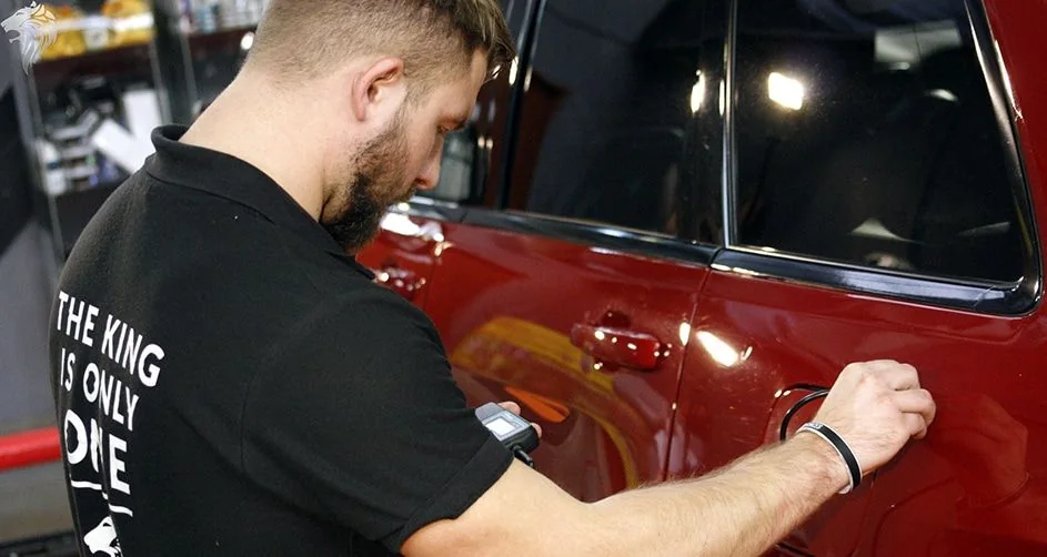 Detailer polerujący czerwone nadwozie maszyną w oświetlonym stanowisku