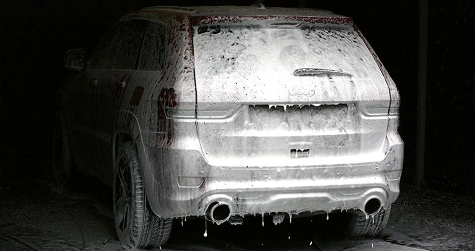 SUV pokryty aktywną pianą podczas mycia bezkontaktowego, widok od tyłu