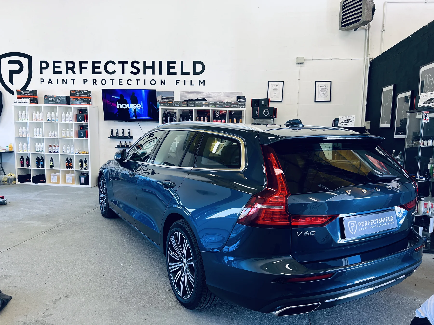 Granatowe Volvo V60 w hali studia Auto Estetyka po pielęgnacji lakieru, w tle ekspozycja folii PerfectShield.